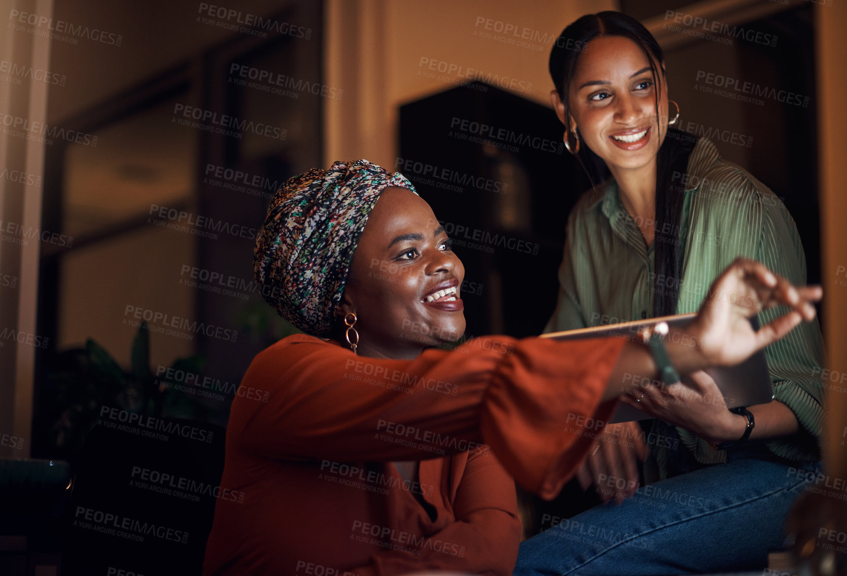 Buy stock photo Shot of two businesswomen working together on a computer in an office at night