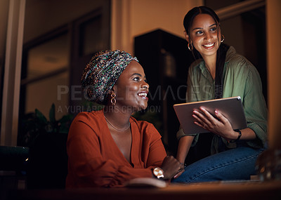 Buy stock photo Shot of two businesswomen working together on a computer in an office at night