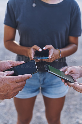 Buy stock photo Cropped shot of a family using their smartphones together outdoors
