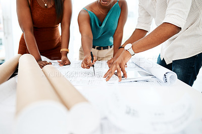 Buy stock photo Cropped shot of a group of colleagues going over blueprints in a modern office