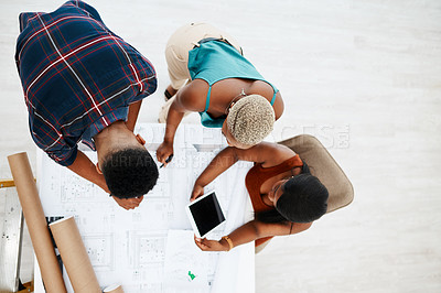 Buy stock photo High angle shot of a group of young colleagues going over blueprints in a modern office