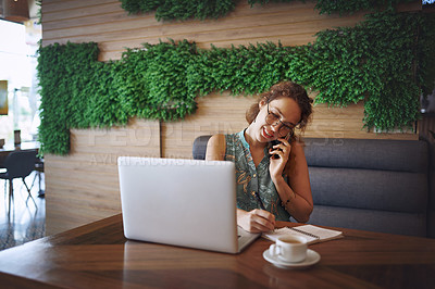Buy stock photo Shot of a young woman using a laptop and smartphone while working at a cafe