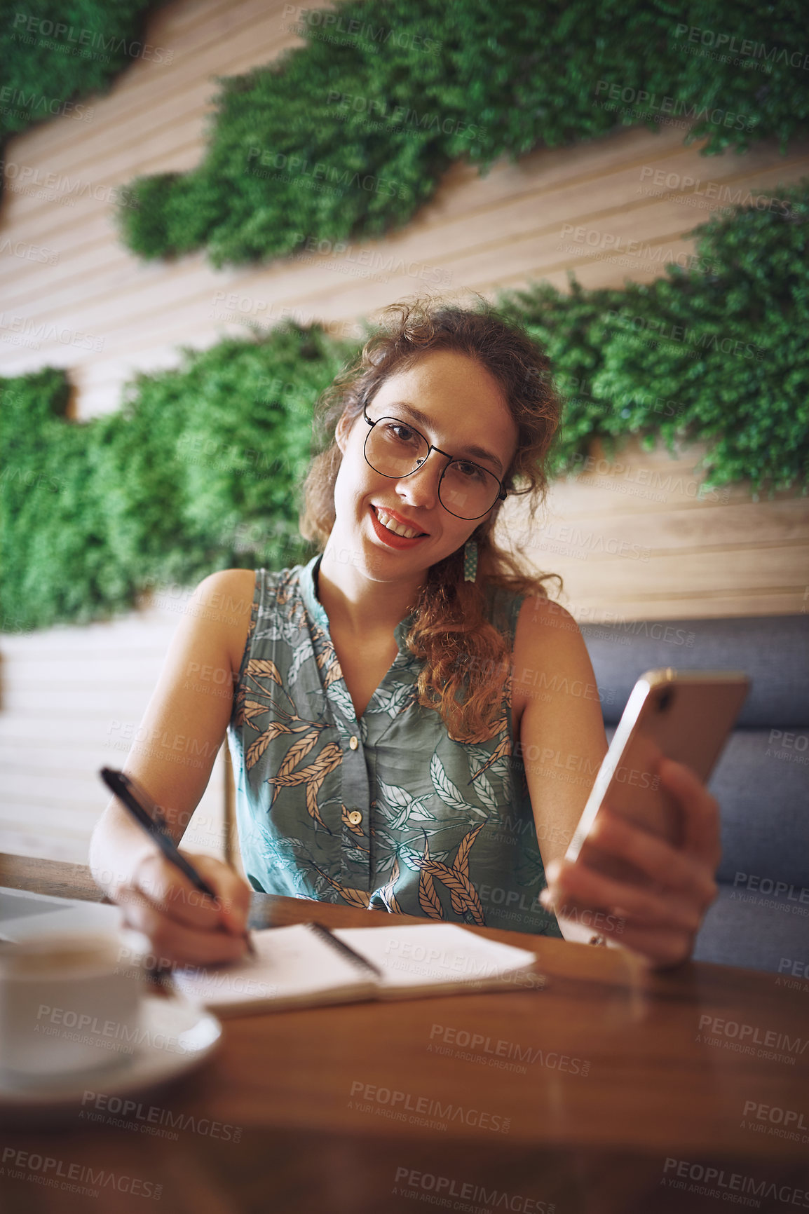 Buy stock photo Shot of a young woman using a smartphone while working at a cafe