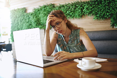 Buy stock photo Shot of a young woman using a laptop and looking stressed while working at a cafe