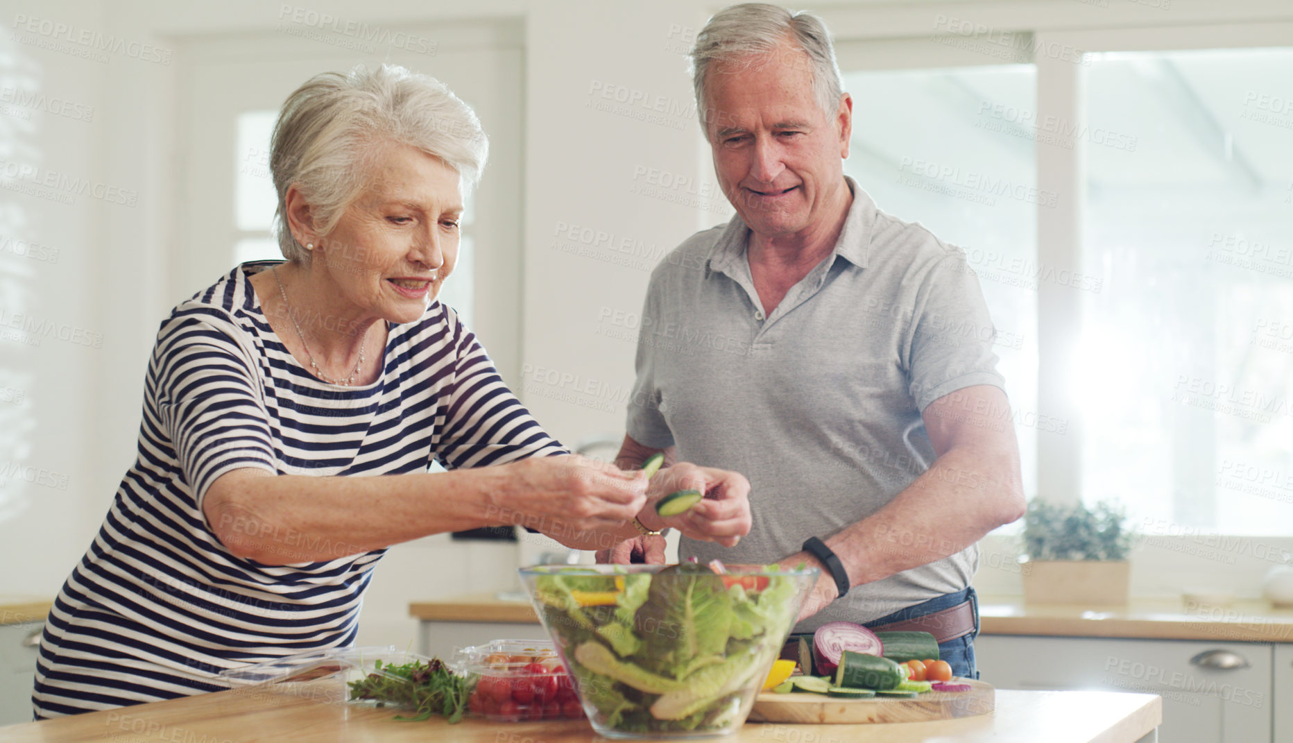 Buy stock photo Cropped shot of a happy senior couple preparing a salad together at home