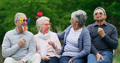 Buy stock photo Shot of a group of happy senior men and women wearing fun glasses at the park