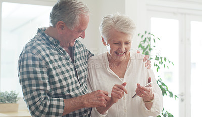 Buy stock photo Cropped shot of a happy senior couple looking at something on a cellphone
