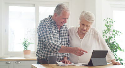 Buy stock photo Cropped shot of a senior couple using a digital tablet while going through paperwork at home