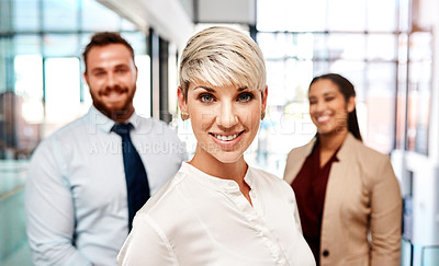 Buy stock photo Portrait of a young businesswoman standing in an office with her colleagues in the background