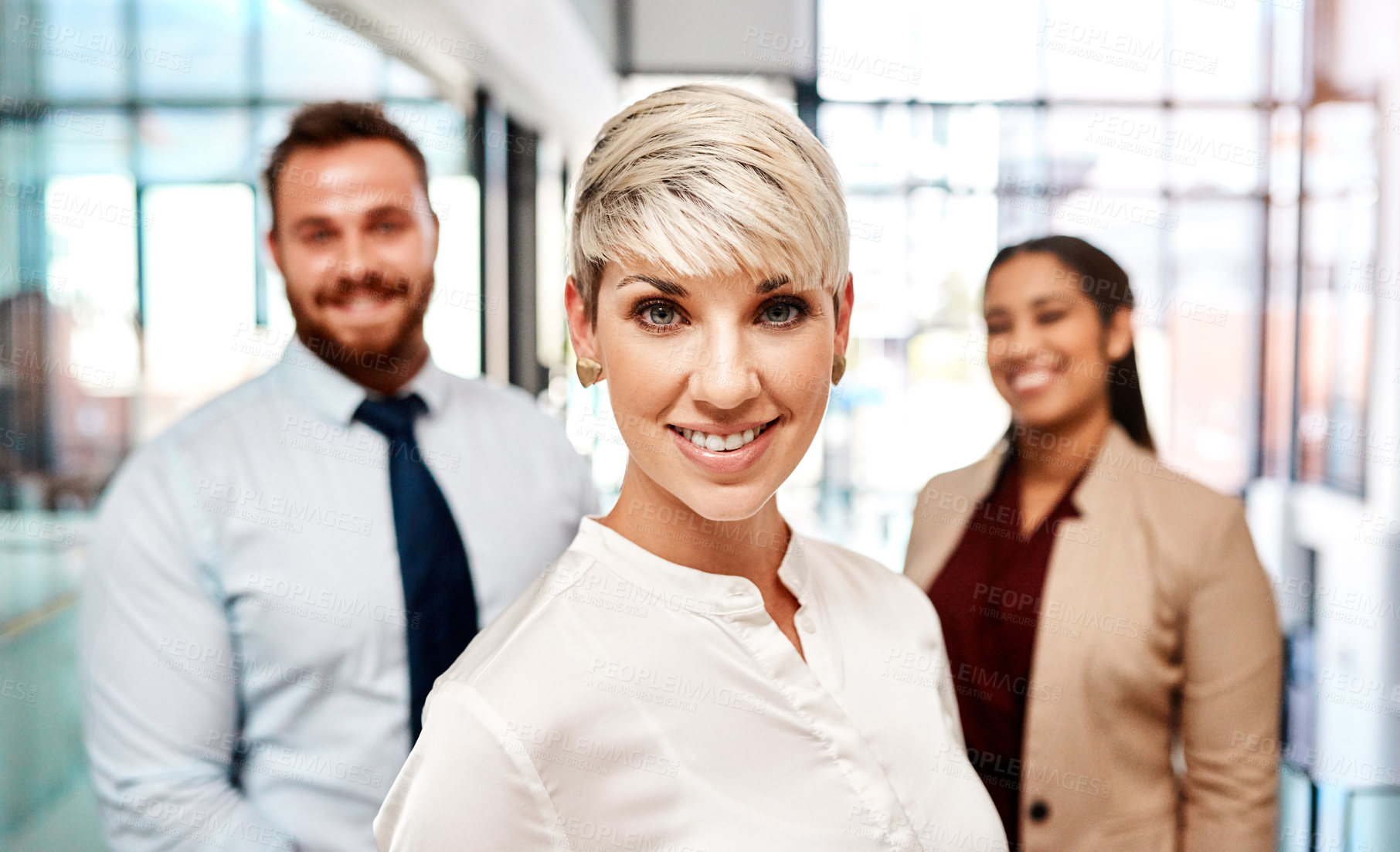 Buy stock photo Portrait of a young businesswoman standing in an office with her colleagues in the background