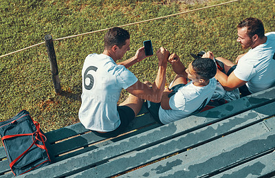 Buy stock photo Shot of a rugby player showing his teammates something on his cellphone