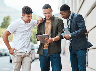 Buy stock photo Shot of a group young businessmen using a digital tablet together against an urban background