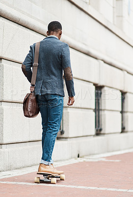 Buy stock photo Rearview shot of a young businessman riding a skateboard through the city