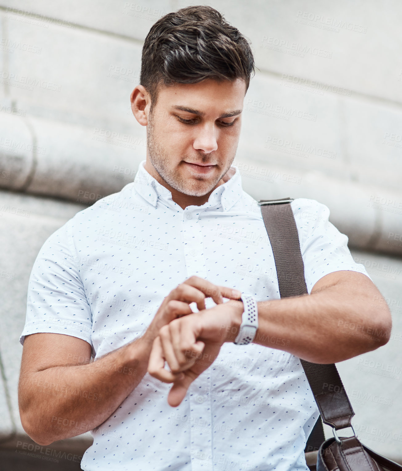 Buy stock photo Shot of a young businessman checking the time against an urban background