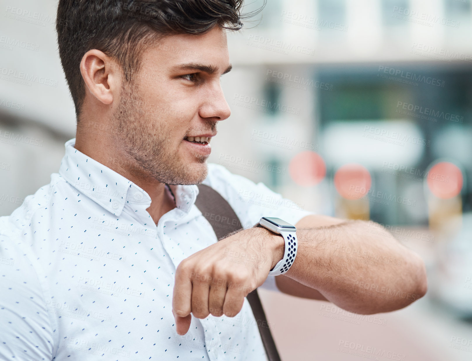 Buy stock photo Shot of a young businessman using a smartwatch against an urban background