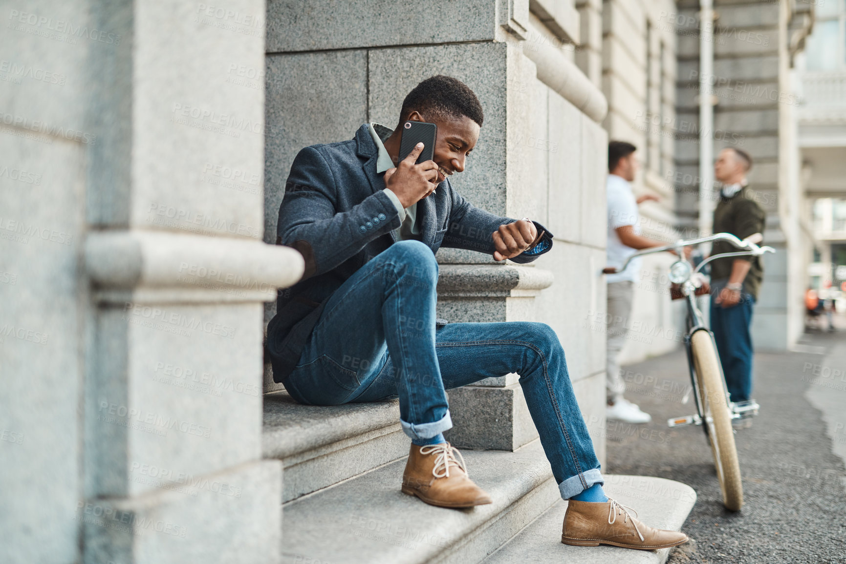 Buy stock photo Shot of a young businessman using a smartphone and checking the time against an urban background
