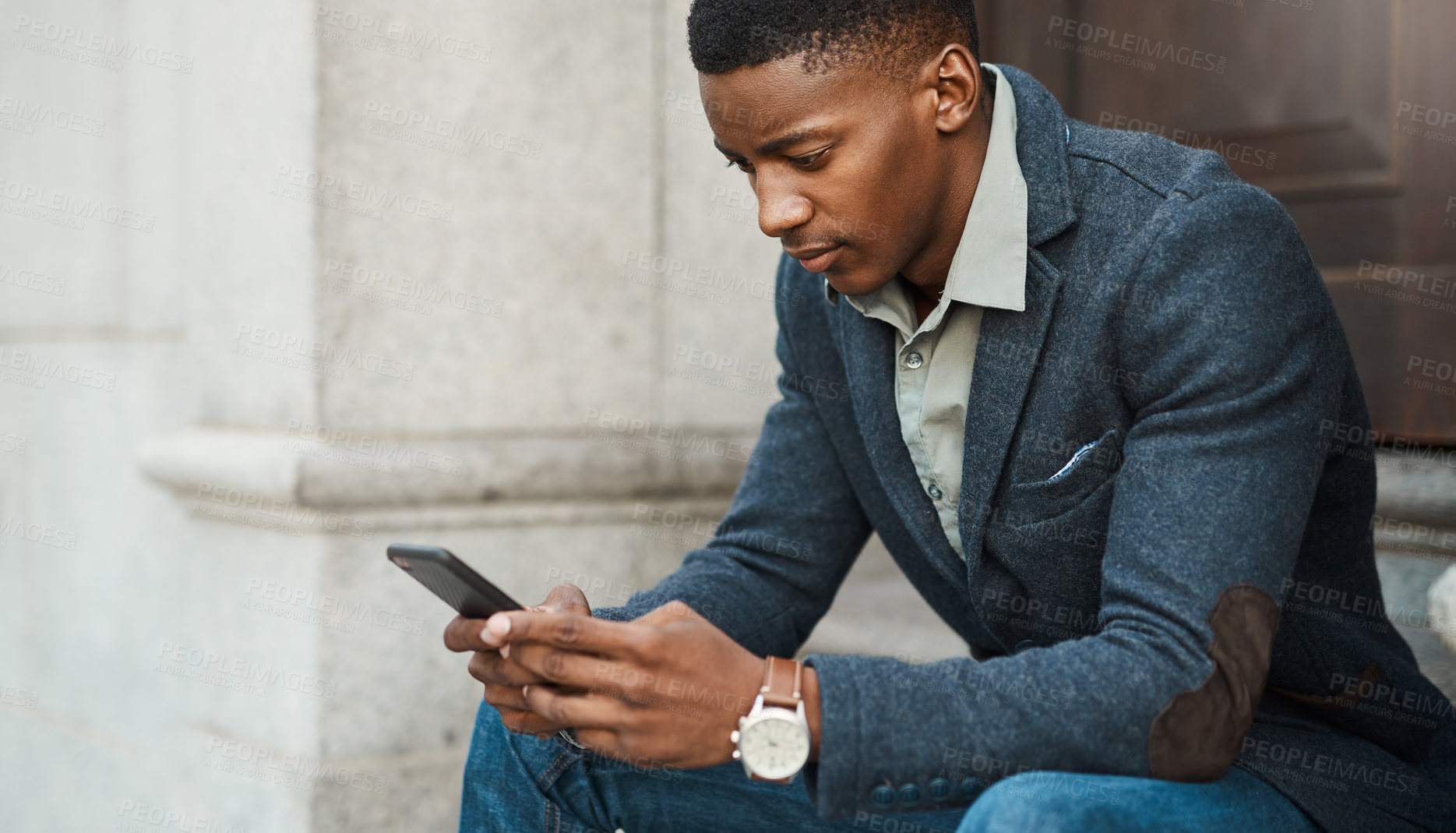 Buy stock photo Shot of a young businessman using a smartphone against an urban background