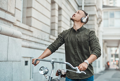Buy stock photo Shot of a young businessman riding a bicycle in the city