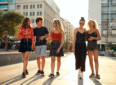 Buy stock photo Full length shot of a group of young friends taking a walk through the city