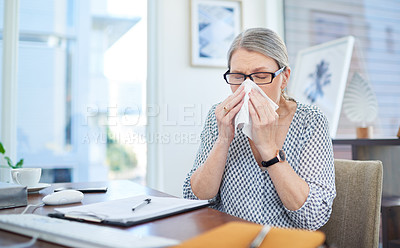 Buy stock photo Shot of a mature businesswoman blowing her nose in an office