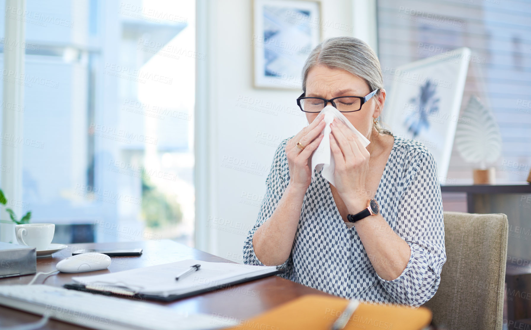 Buy stock photo Shot of a mature businesswoman blowing her nose in an office