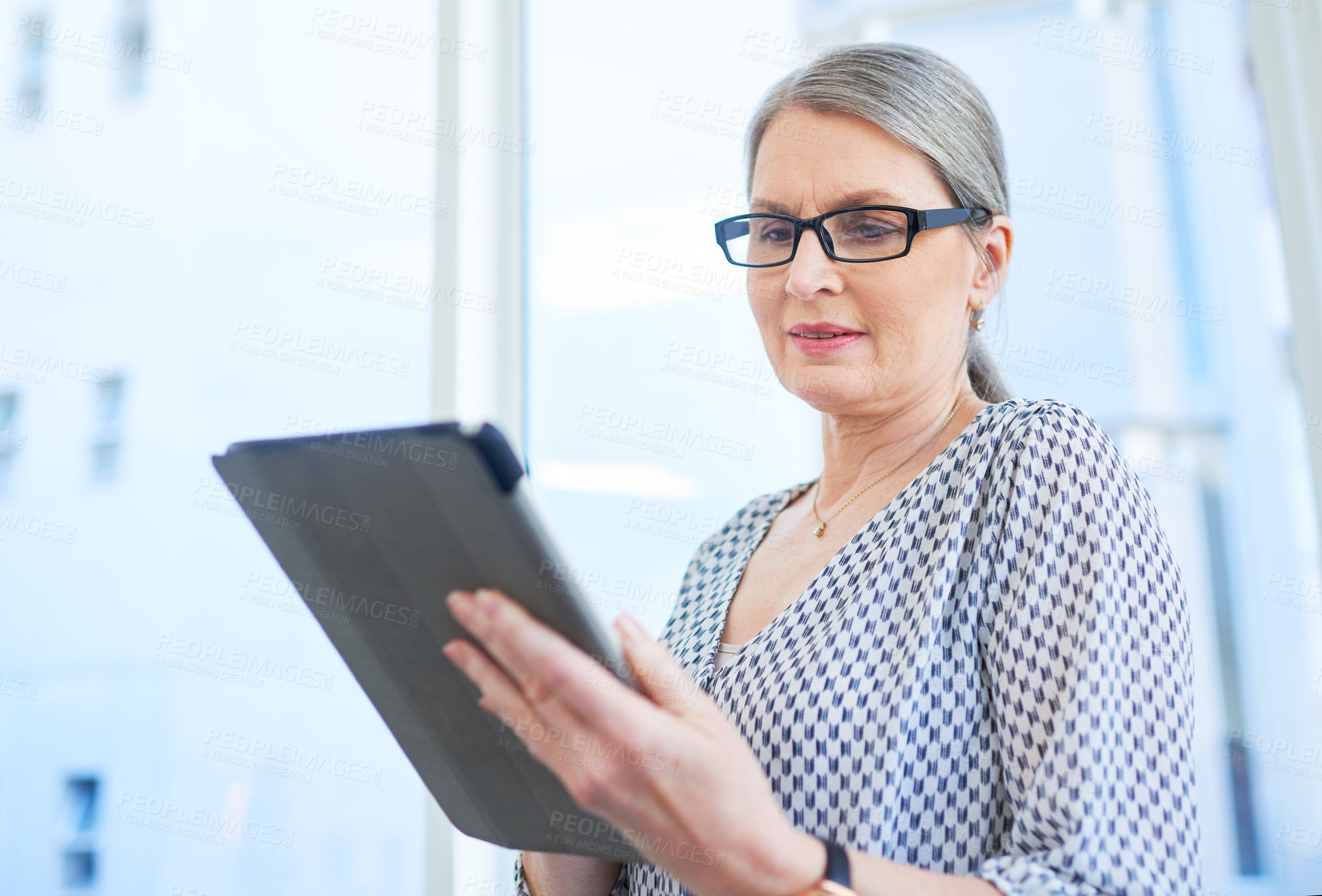 Buy stock photo Shot of a mature businesswoman using a digital tablet in an office