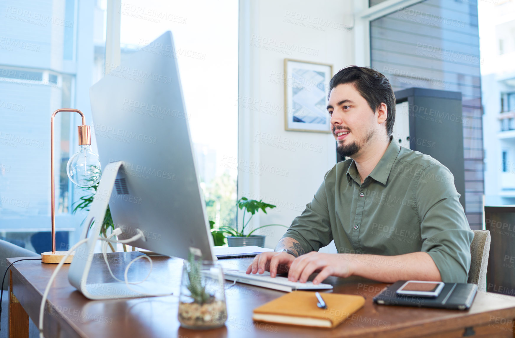 Buy stock photo Shot of a young businessman working on a computer in an office