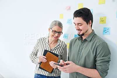 Buy stock photo Shot of two businesspeople using a cellphone together in an office
