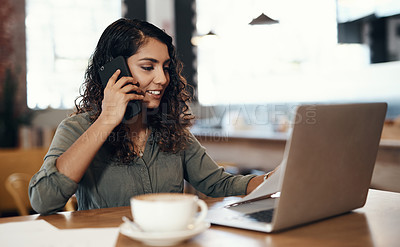 Buy stock photo Shot of a young woman using a laptop and smartphone while working in a cafe