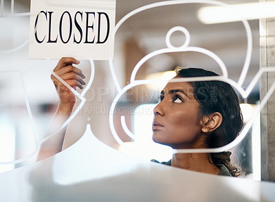 Buy stock photo Shot of a young woman hanging up a closed sign on the door of a cafe