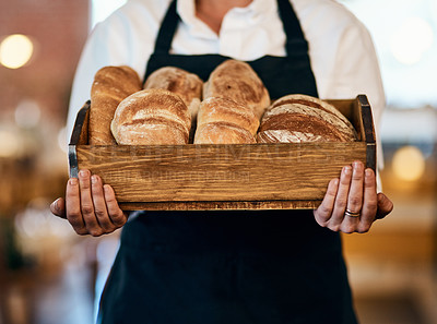 Buy stock photo Cropped shot of a woman holding a selection of freshly baked breads in her bakery