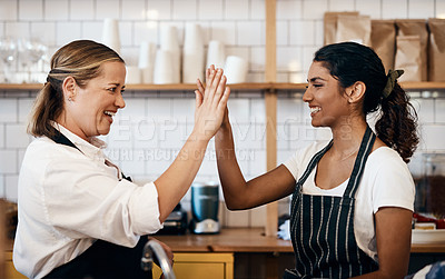 Buy stock photo Shot of two women giving each other a high five while working together at a cafe