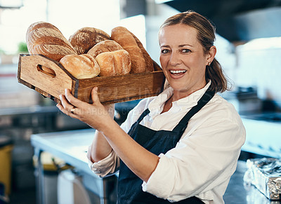 Buy stock photo Baker, pastry chef and cafe owner carrying a tray of fresh rolls and bread loaf assortment in a coffee shop. Portrait of a small business entrepreneur in an apron with freshly made consumables 