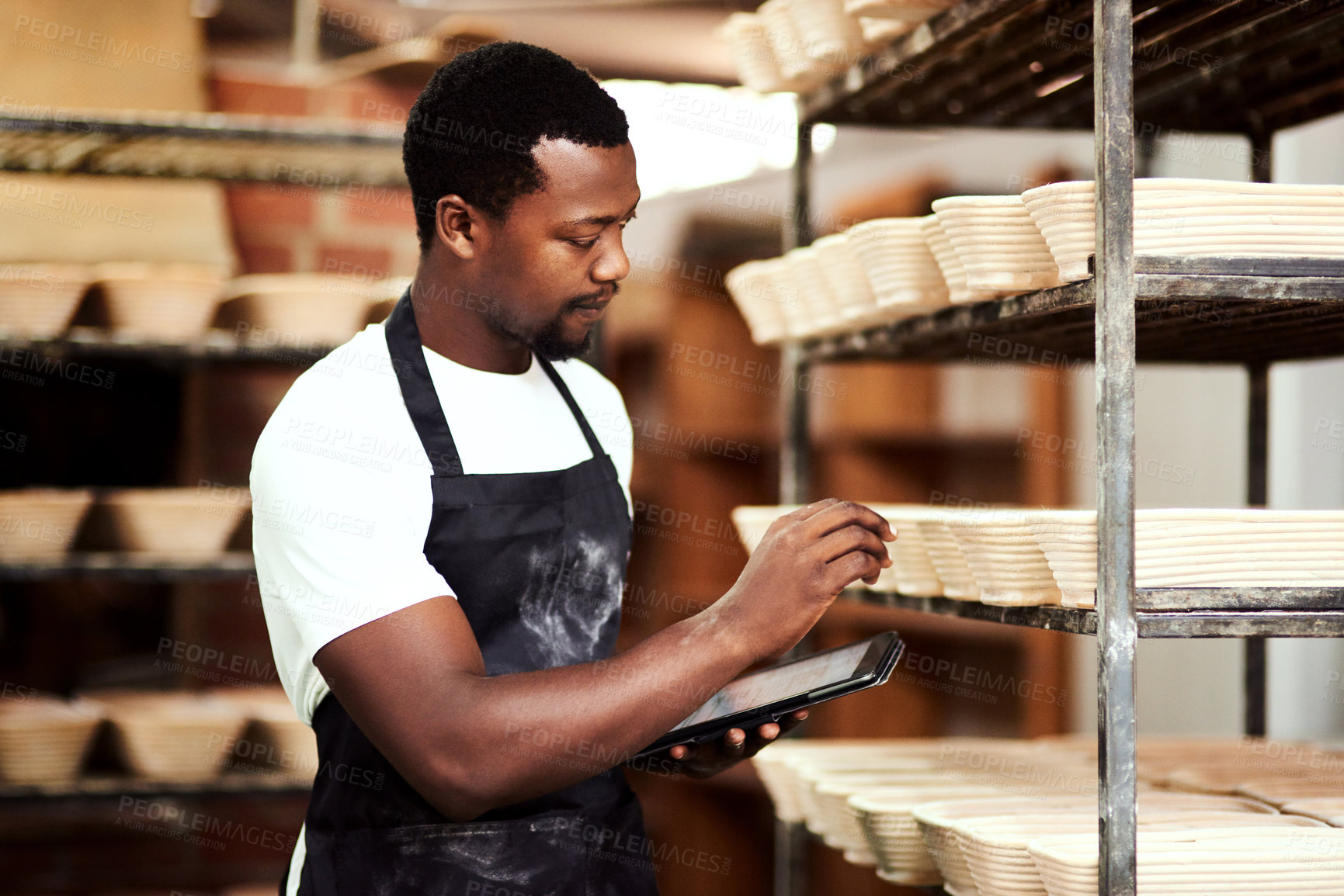 Buy stock photo Cropped shot of a man using a digital tablet while working in a bakery