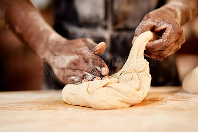 Buy stock photo Cropped shot of a male baker busy shaping dough at work