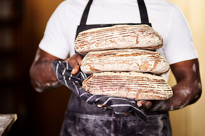 Buy stock photo Cropped shot of a male baker holding freshly baked bread in his bakery