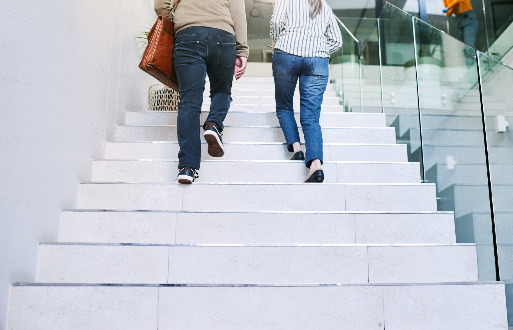 Buy stock photo Rearview shot of two unrecognisable businesspeople walking up a staircase together in an office