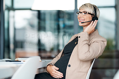 Buy stock photo Shot of a pregnant businesswoman wearing a headset while working in an office