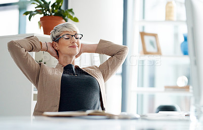 Buy stock photo Shot of a young businesswoman taking a break at her office desk