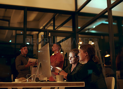 Buy stock photo Cropped shot of two businesswoman looking at something on a computer in an office at night