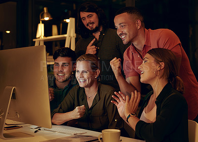 Buy stock photo Shot of a group of businesspeople looking at something on a computer in an office at night