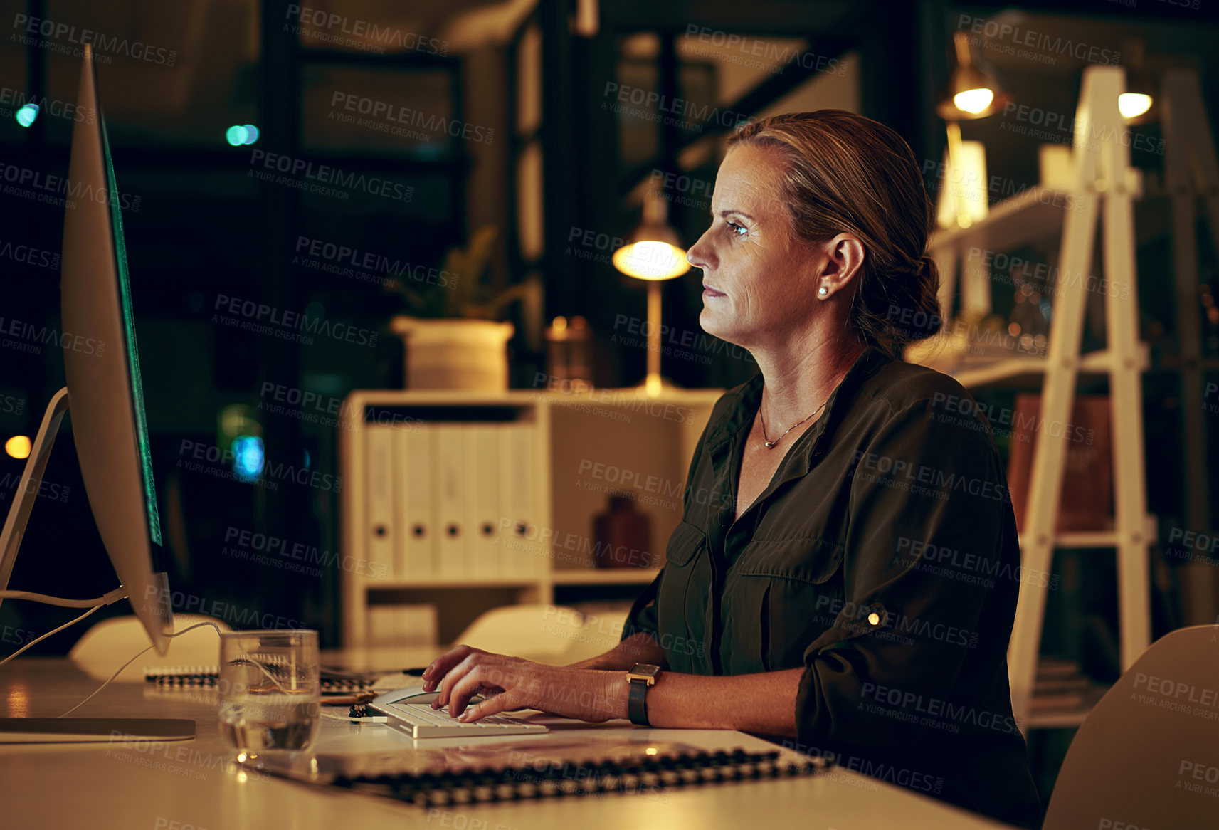 Buy stock photo Shot of a businesswoman using her computer while working late at the office