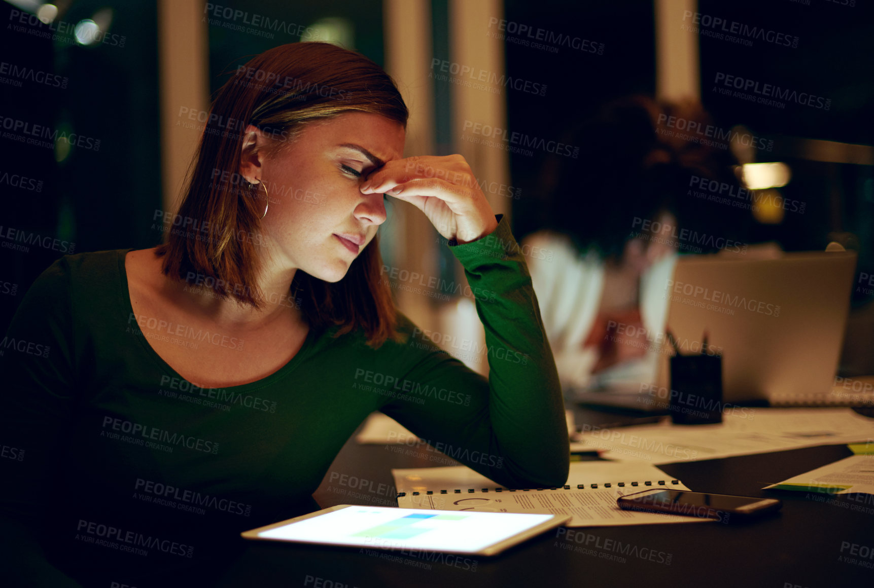 Buy stock photo Shot of a businesswoman suffering with a headache while working late