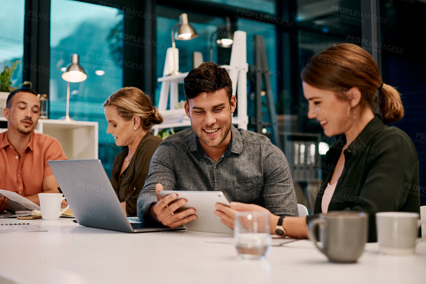 Buy stock photo Shot of two businesspeople looking at something on a digital tablet while sitting in the boardroom