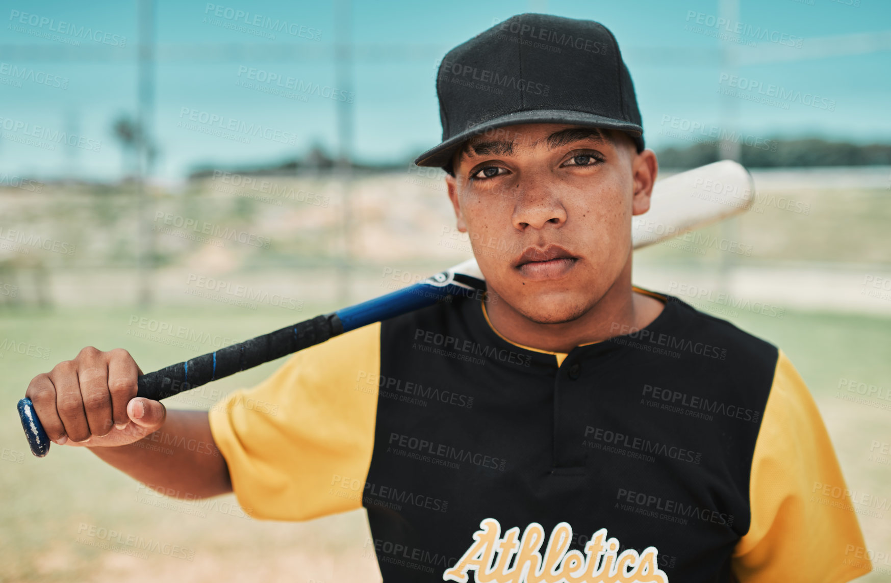 Buy stock photo Shot of a young baseball player holding a baseball bat while posing outside on the pitch