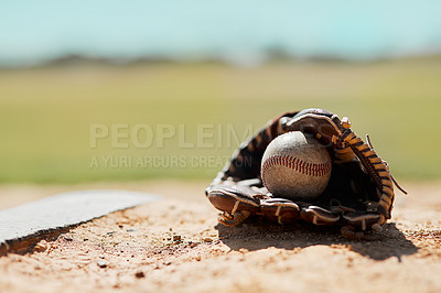 Buy stock photo Shot of a baseball mitt and ball lying on the pitch during the day