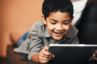 Buy stock photo Shot of an adorable little boy using a digital tablet on the sofa at home