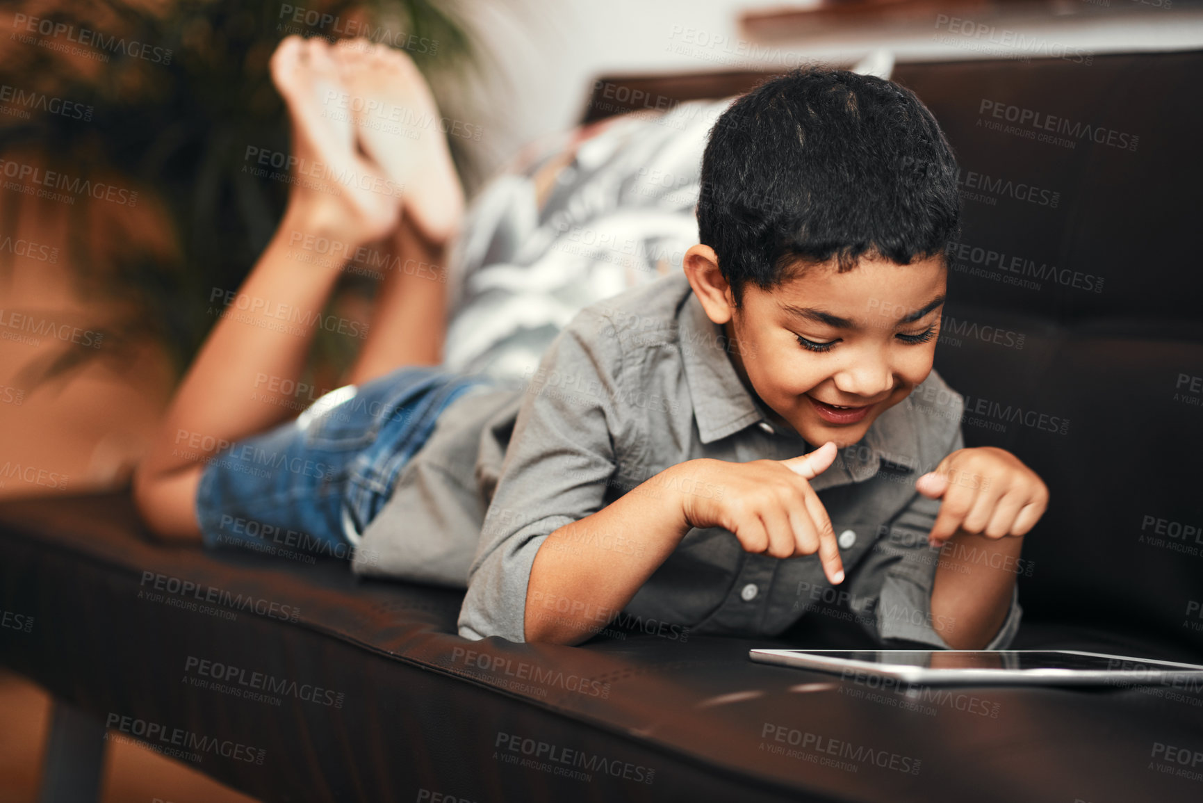Buy stock photo Shot of an adorable little boy using a digital tablet on the sofa at home