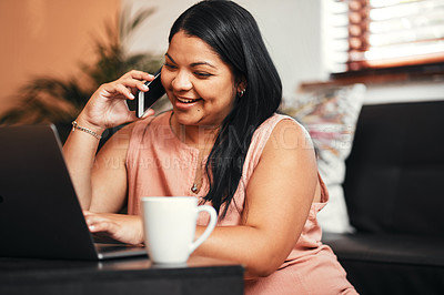 Buy stock photo Shot of a young woman talking on a cellphone while using a laptop at home
