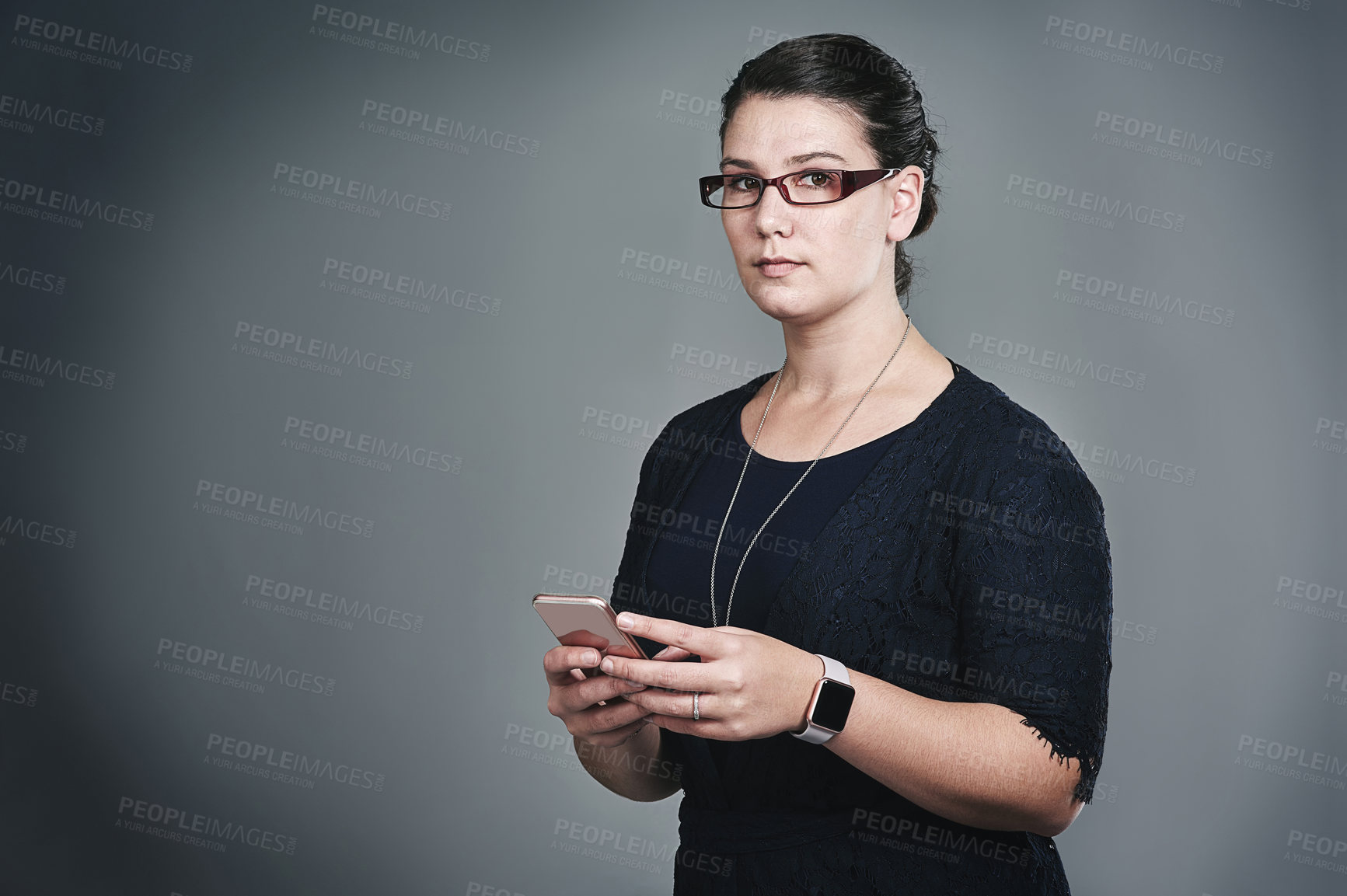 Buy stock photo Studio portrait of a young businesswoman using a mobile phone against a grey background